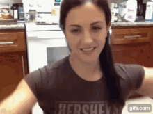 a woman is wearing a hershey t-shirt in a kitchen .