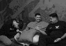 a man wearing a question mark shirt sits with two other men