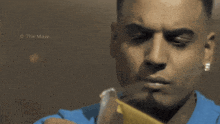 a close up of a man holding a piece of paper with the watermark the maw
