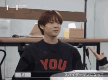 a young man wearing a black sweater that says " you "