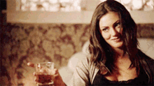 a woman is sitting on a couch holding a glass of wine .
