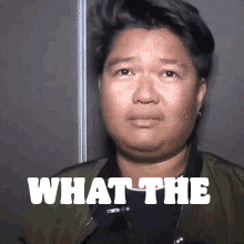 a man in a green jacket is making a funny face with the words what the written on his face .