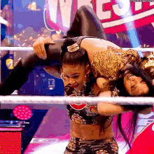 a female wrestler is carrying another wrestler on her shoulders .