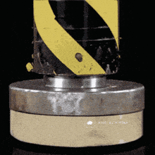 a yellow and black striped object is sitting on a metal base with the words made with pika written on it