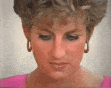 a close up of a woman 's face with a pink shirt and hoop earrings