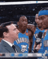 a man in a suit and tie is talking to two basketball players .