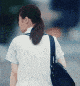 a woman in a school uniform is walking down a street with a black bag