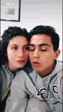 a man and a woman are posing for a picture and the man is wearing a gap hoodie .
