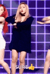 a woman in a black dress is giving a thumbs up sign while dancing on a stage .