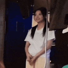 a woman in a white t-shirt is standing in a room .