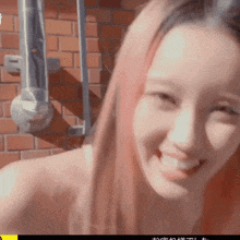 a woman with pink hair is smiling in front of a brick building