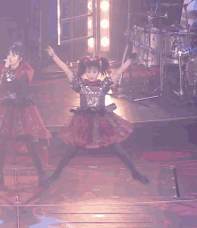 a girl in a red dress is singing into a microphone on stage