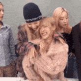 a woman wearing a neverthe hat is hugging another girl