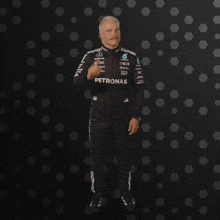 a man in a petronas suit stands in front of a black background