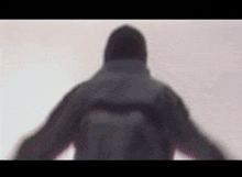 a blurry picture of a man in a hooded jacket standing in the snow .
