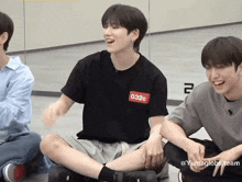 a group of young men are sitting on the floor with their legs crossed and smiling .