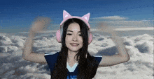 a woman wearing pink headphones with cat ears is waving her hands in the air .