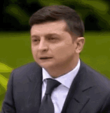 a man in a suit and tie is looking at the camera .