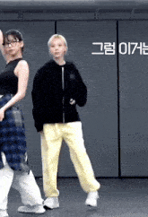two girls are dancing in a room with korean writing on the wall .