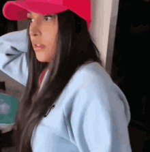 a woman wearing a pink hat and a blue sweatshirt is looking at the camera .