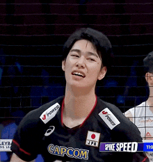 a man wearing a black capcom 15 jersey