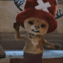 a stuffed animal wearing a red hat with antlers is standing on a tiled floor .