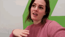 a woman wearing a pink sweater with a green background