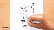 a person is drawing a pikachu on a piece of paper with a sharpie marker