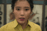 a woman in a yellow shirt has a tear running down her cheek