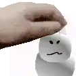 a hand is putting a marshmallow on top of a snowman .