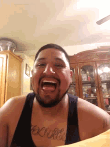 a man with a tattoo on his chest that says " believe " is laughing