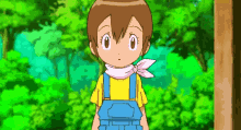 a little girl in overalls and a yellow shirt is standing in front of trees .