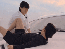 a man laying on another man 's lap with a white shirt on