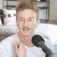 a man wearing glasses and ear buds is sitting in front of a microphone