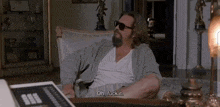 a man with a beard and sunglasses is sitting in a chair and says oh fuck it
