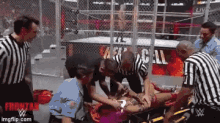 a man is laying on a stretcher in a wrestling ring being examined by a group of people .