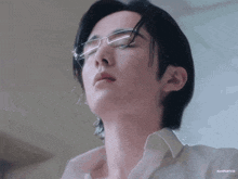 a close up of a person wearing glasses and a white shirt .