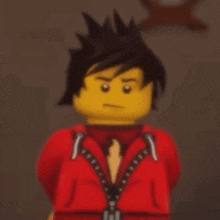 a lego man with black hair and a red jacket and tie is standing in front of a wall .