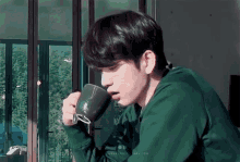 a man in a green sweater is drinking from a cup