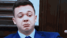 a man in a blue suit and tie making a funny face