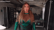 a woman in a green and leopard print outfit stands in a room