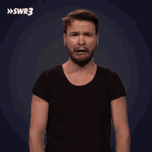 a man making a funny face in front of a blue background with the letters swr3 on it