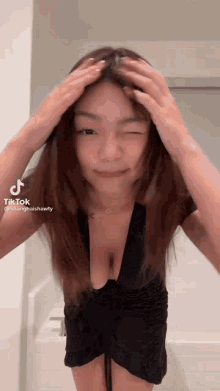 a woman in a black dress with a very plunging neckline is standing in front of a bathtub .