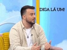 a man with a beard is sitting in front of a sign that says " diga la um "