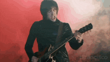 a man in a black jacket is playing a guitar in front of a red background that says francisco on it