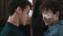 a man with a bandage on his eye talks to another man