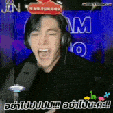 a man wearing headphones is screaming in front of a screen that says t98