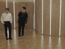 two men are standing on a wooden floor in a room .