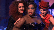 three women are posing for a picture and one has a red top hat on