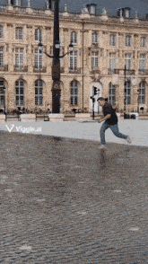 a man is running through a puddle in front of a building with the words viggle.ai below him